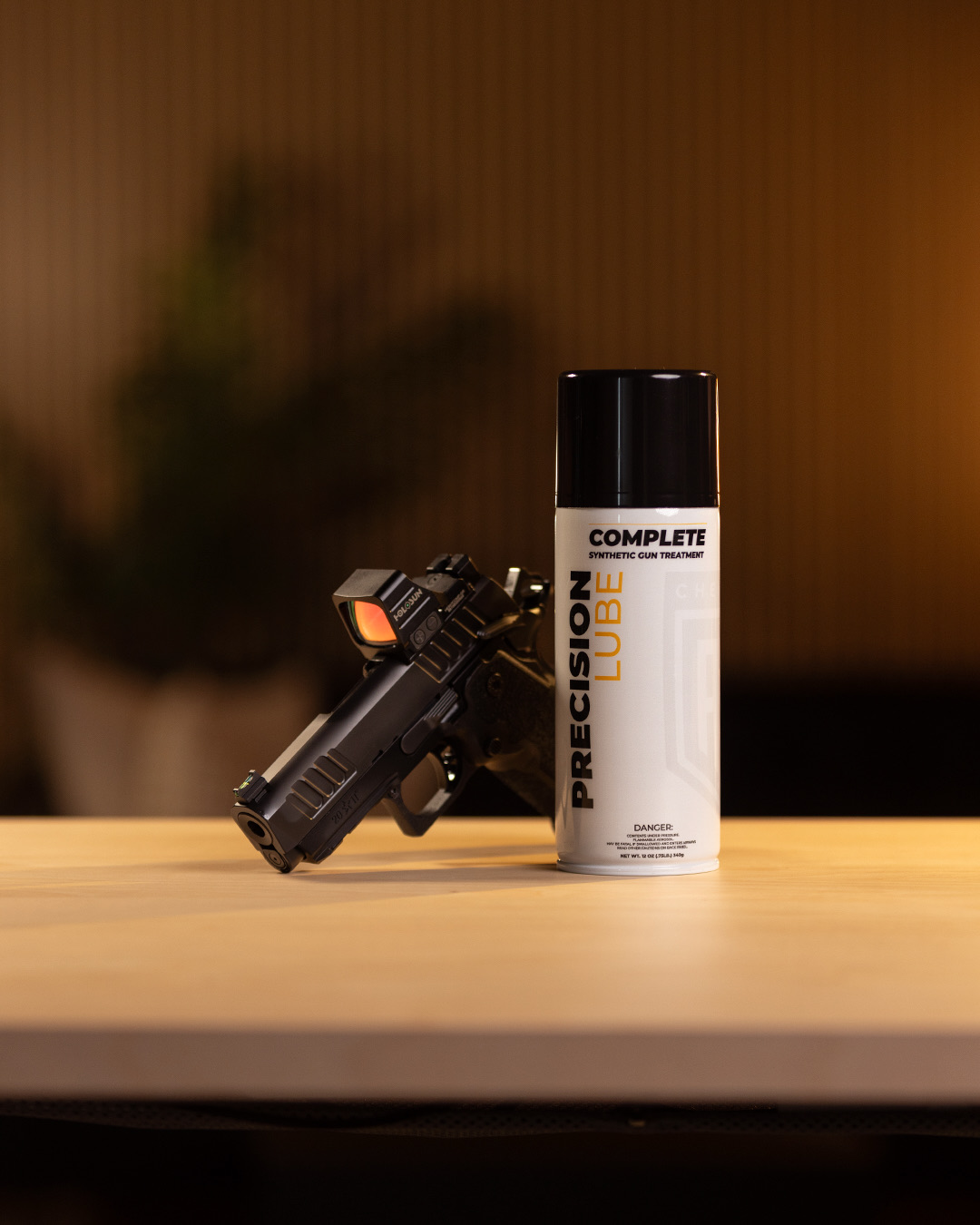 PRECISION Lube CLP 12 oz aerosol can next to a pistol on a workbench